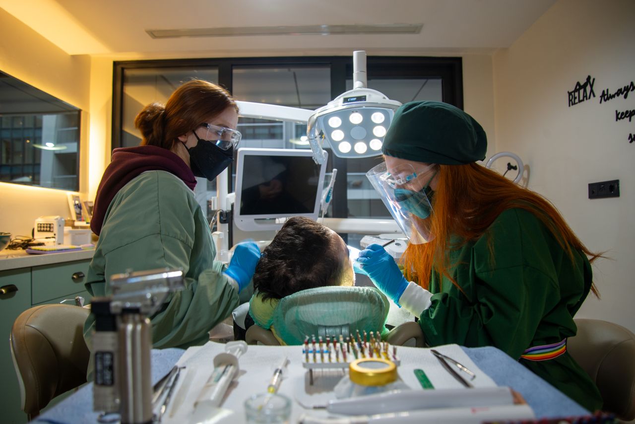 Patients receiving treatment at a dental clinic with two professional dentists wearing protective gear.